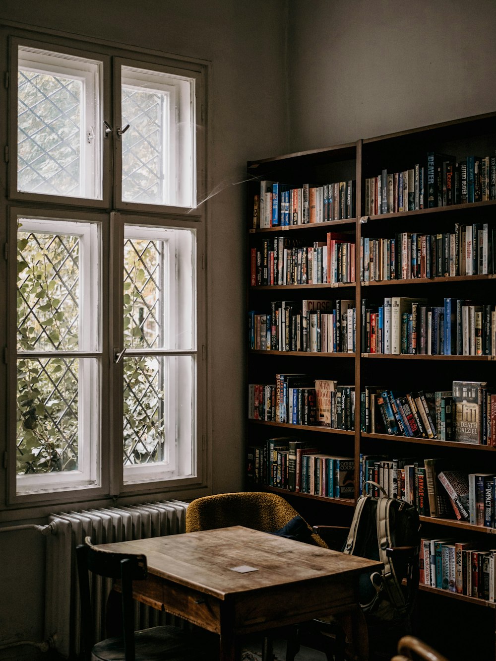 a wooden table sitting in front of a window filled with books