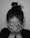 A person with hair tied in a bun covers their face with both hands, displaying an emotional moment. The lighting is subdued, emphasizing a sense of privacy and moodiness.