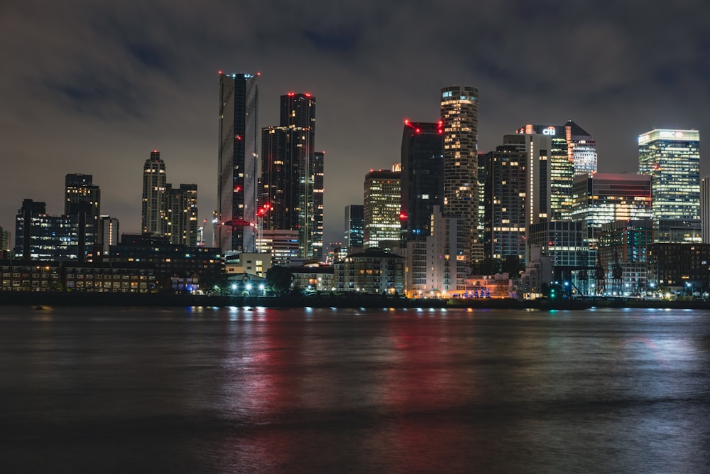 a city skyline at night with lights reflecting off the water