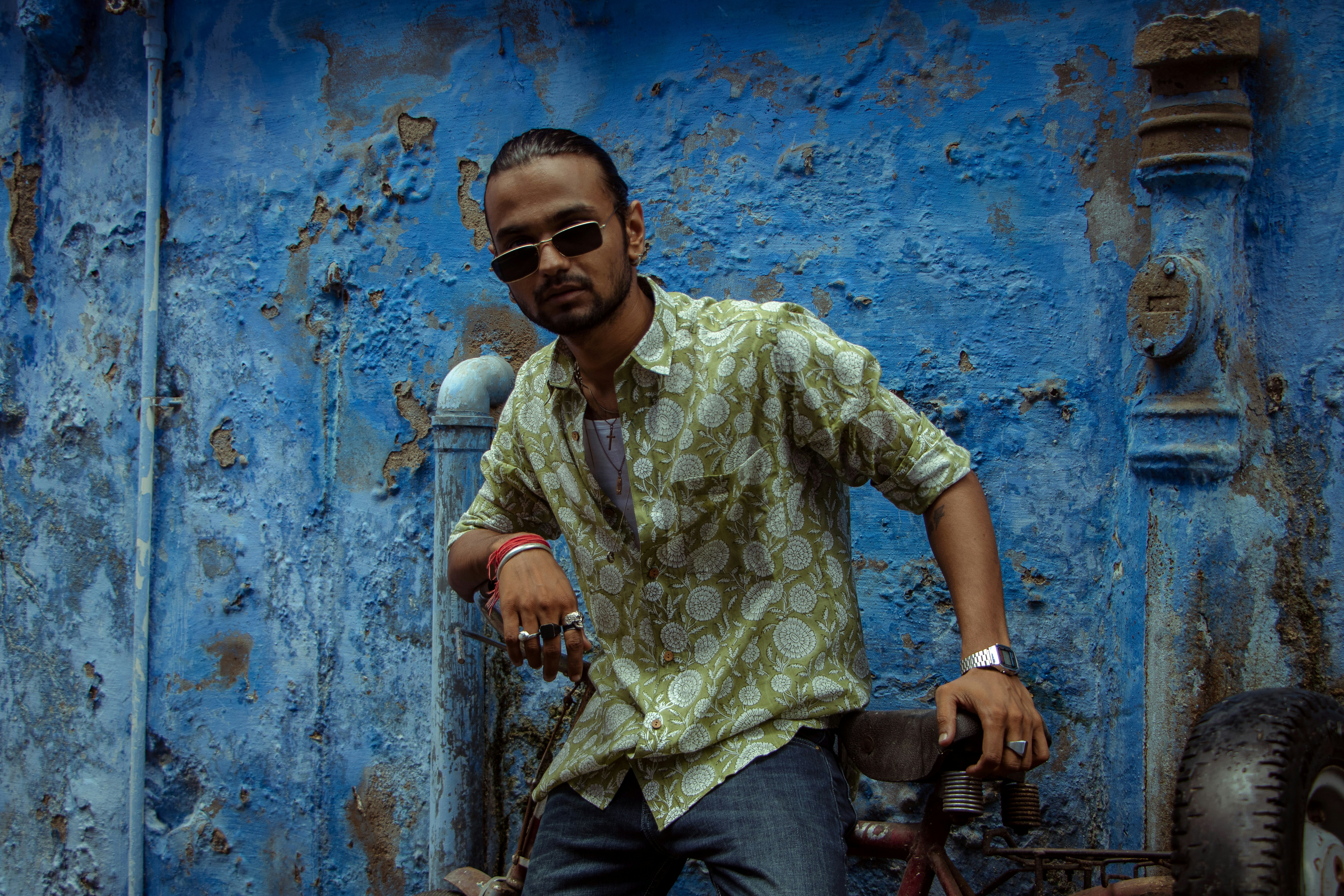 a man standing next to a bike in front of a blue wall