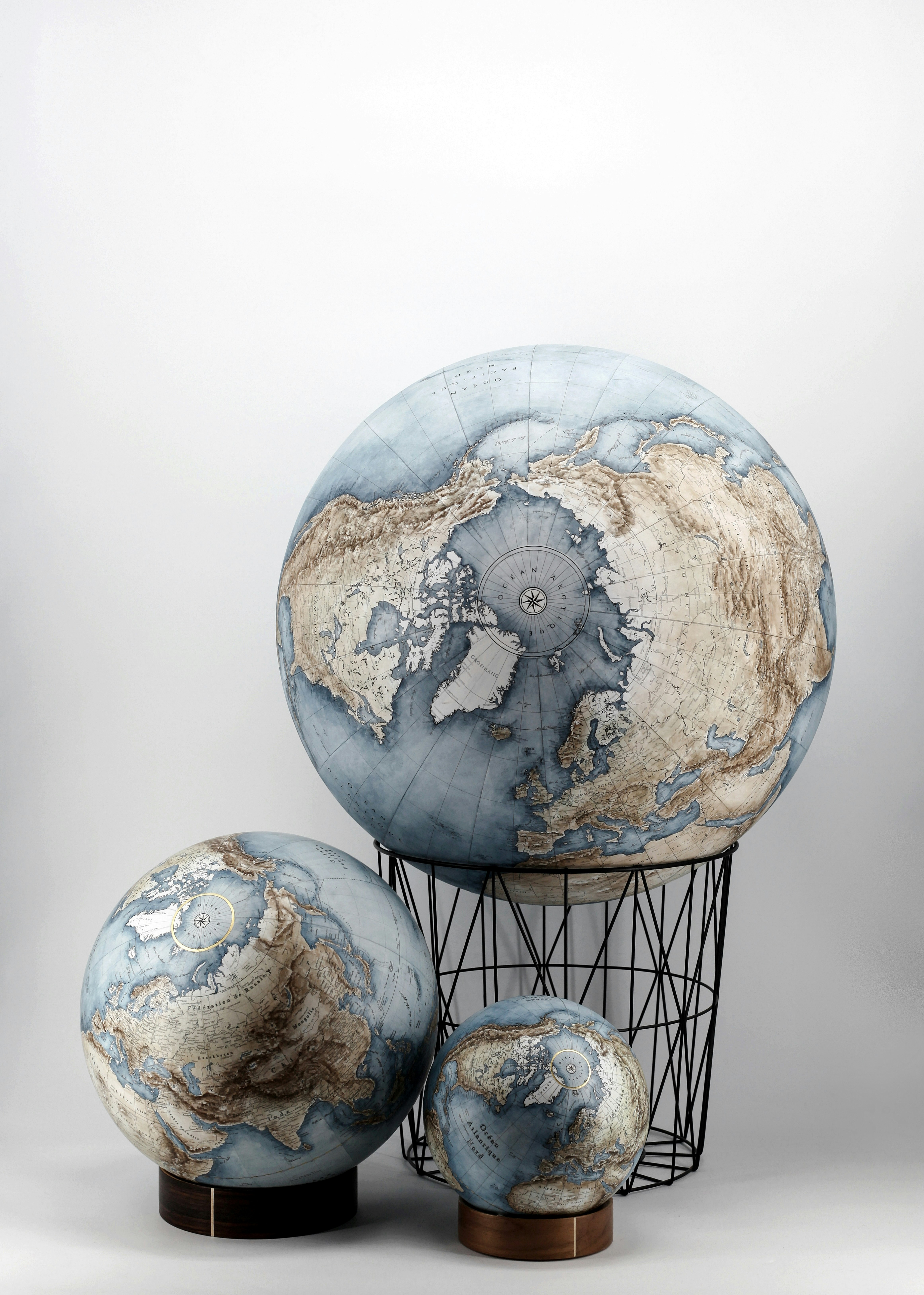 Three terrestrial globes over white background. Color and relief shading using watercolors.