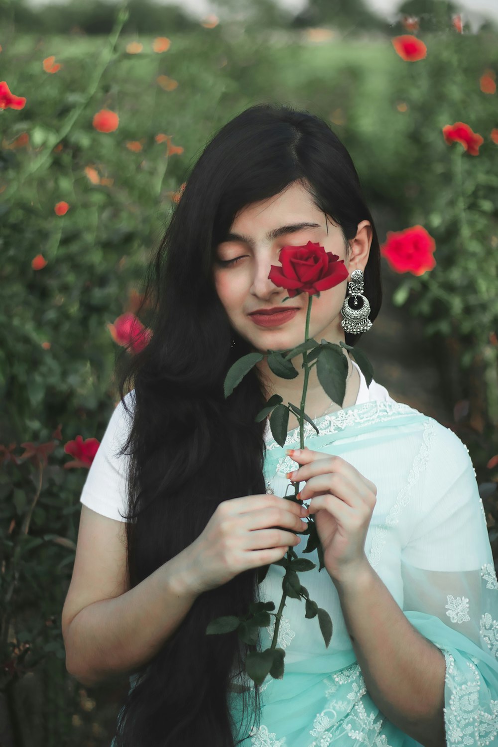 a woman with long black hair holding a rose