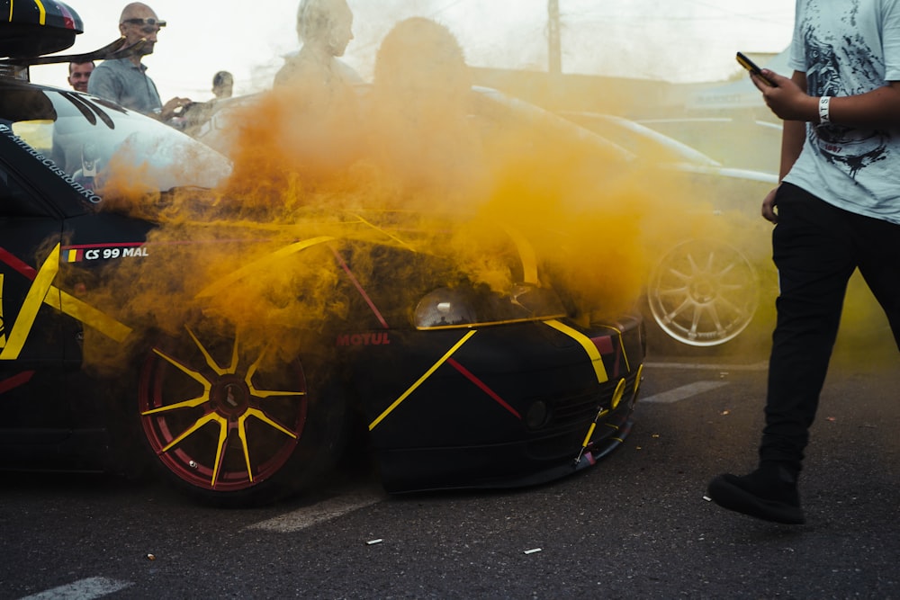 Ein Mann steht neben einem mit gelbem Rauch bedeckten Auto