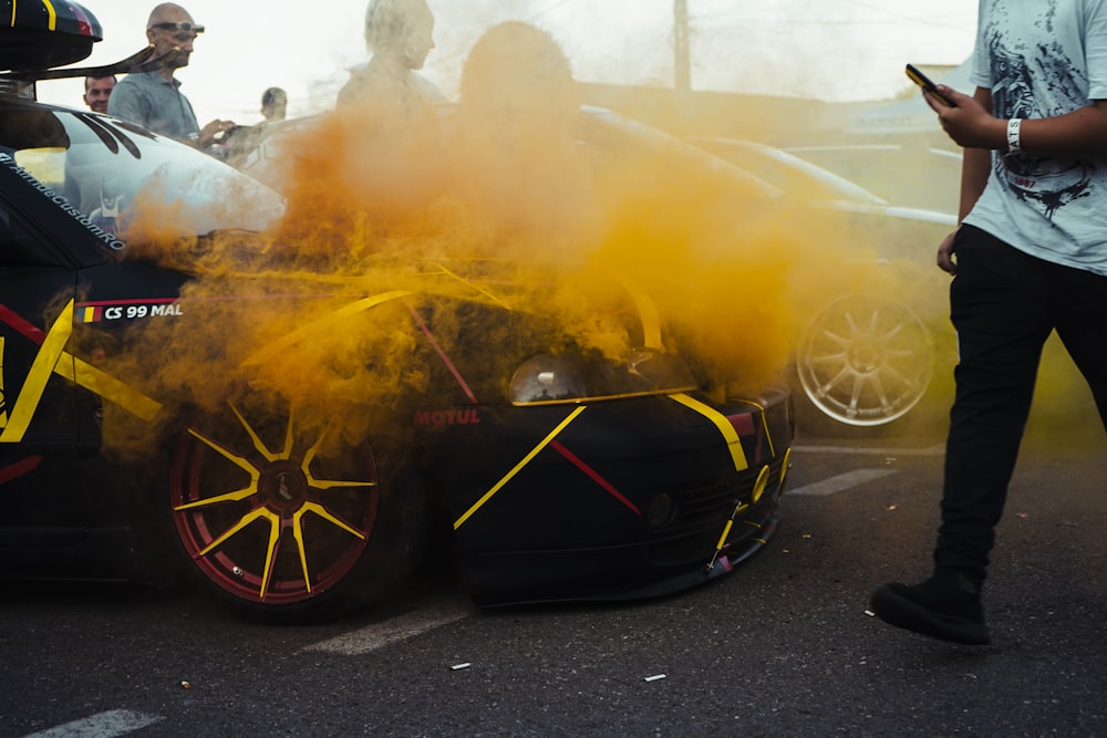 a man standing next to a car covered in yellow smoke