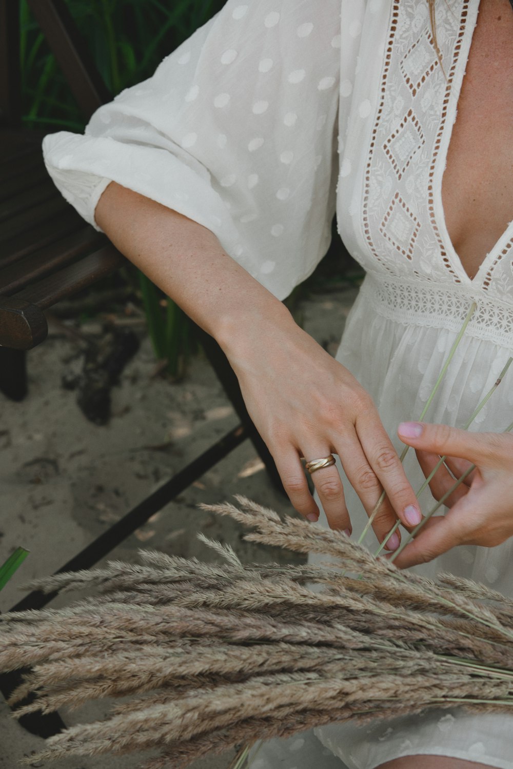 a woman in a white dress holding a bunch of grass