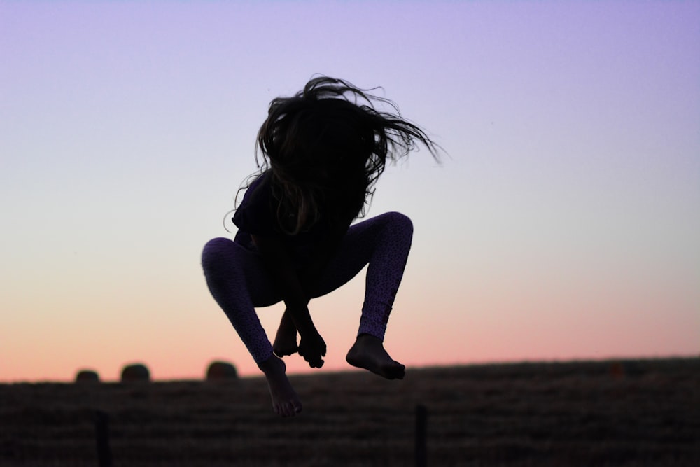 a silhouette of a person jumping in the air