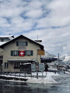a building with snow on the ground and mountains in the background