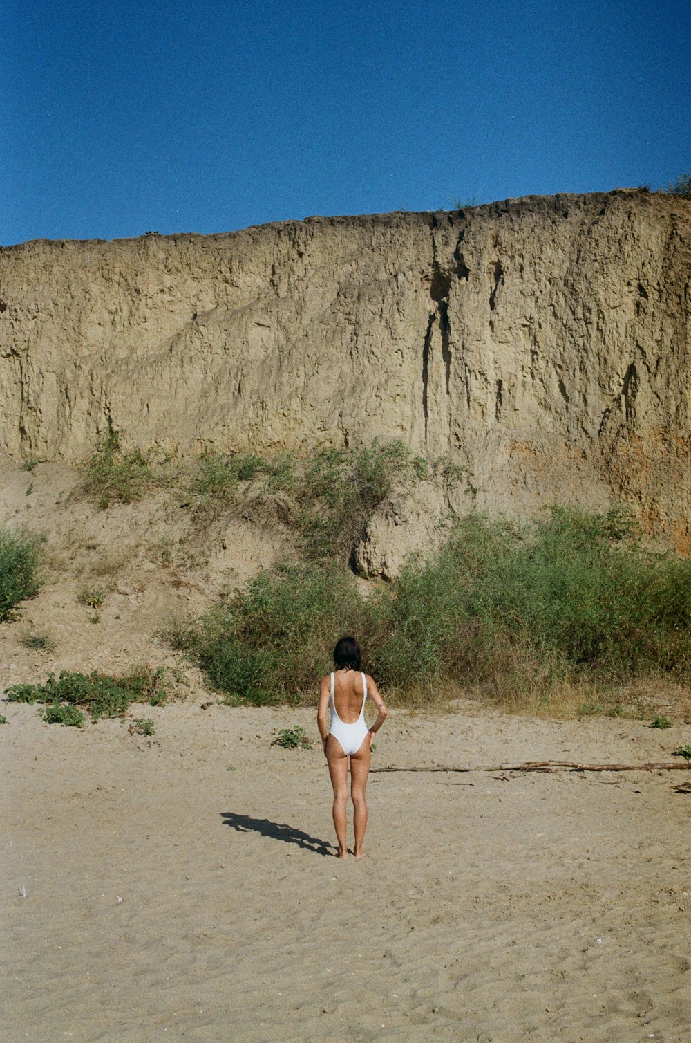 uma mulher em um traje de banho que anda em uma praia