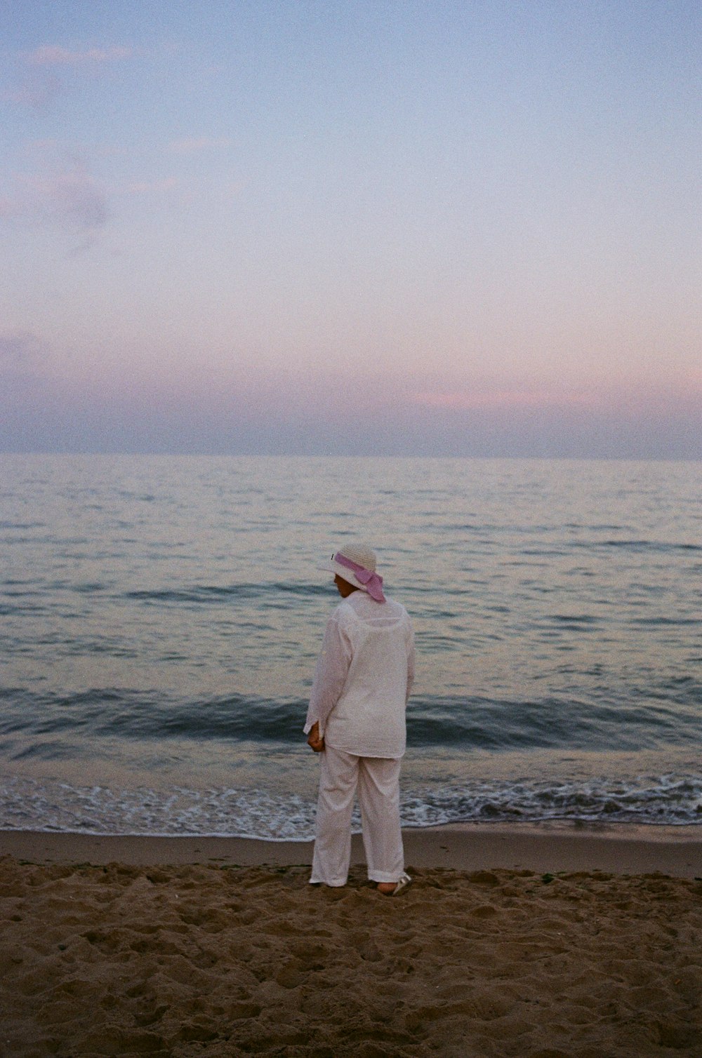 um homem em pé no topo de uma praia de areia ao lado do oceano