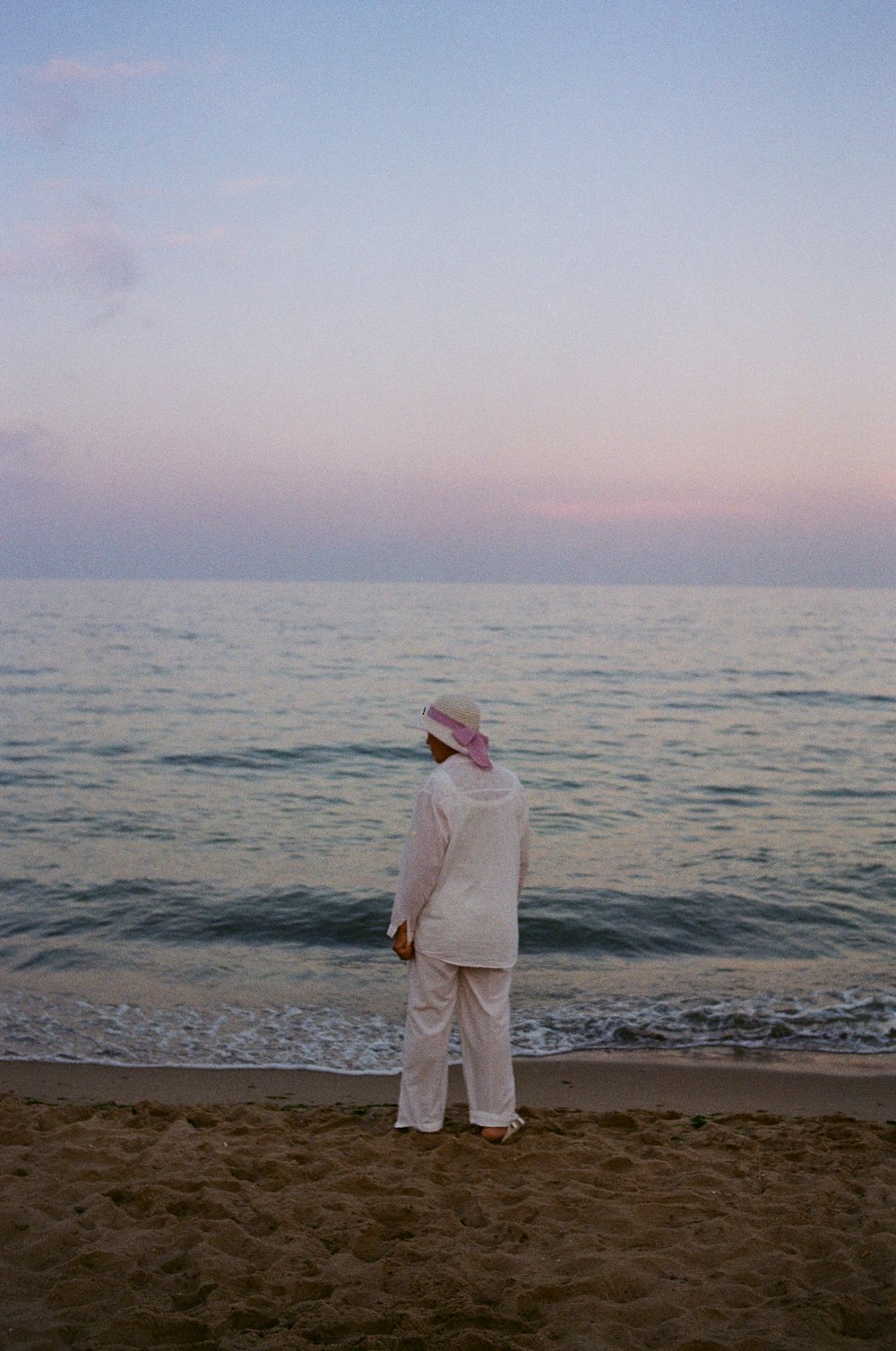 a man standing on top of a sandy beach next to the ocean