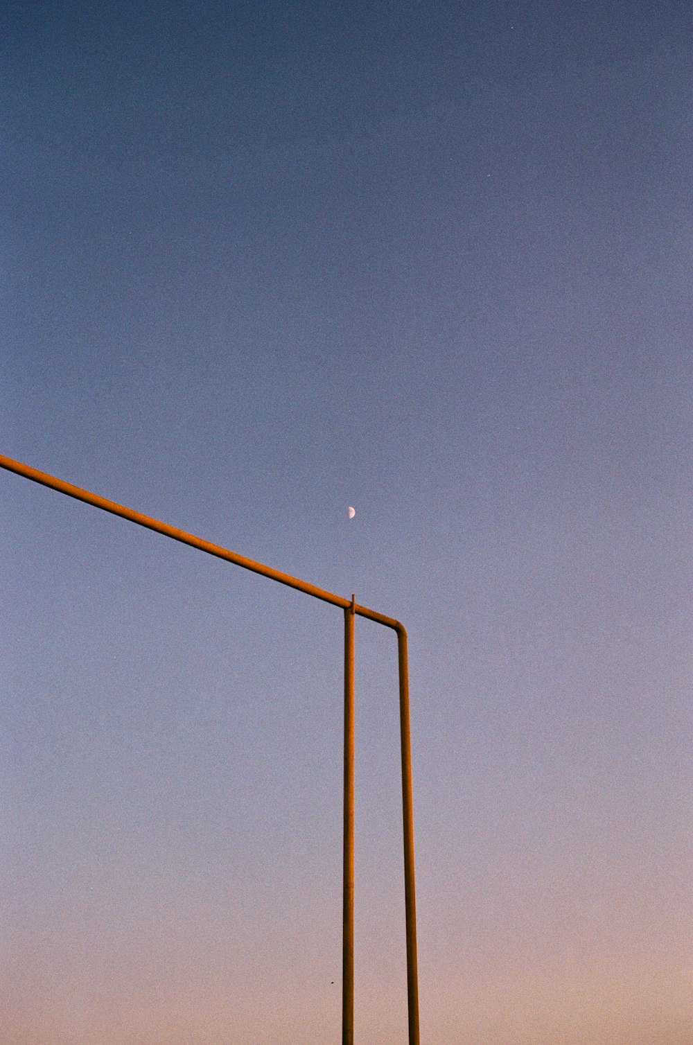 a street light with a half moon in the sky