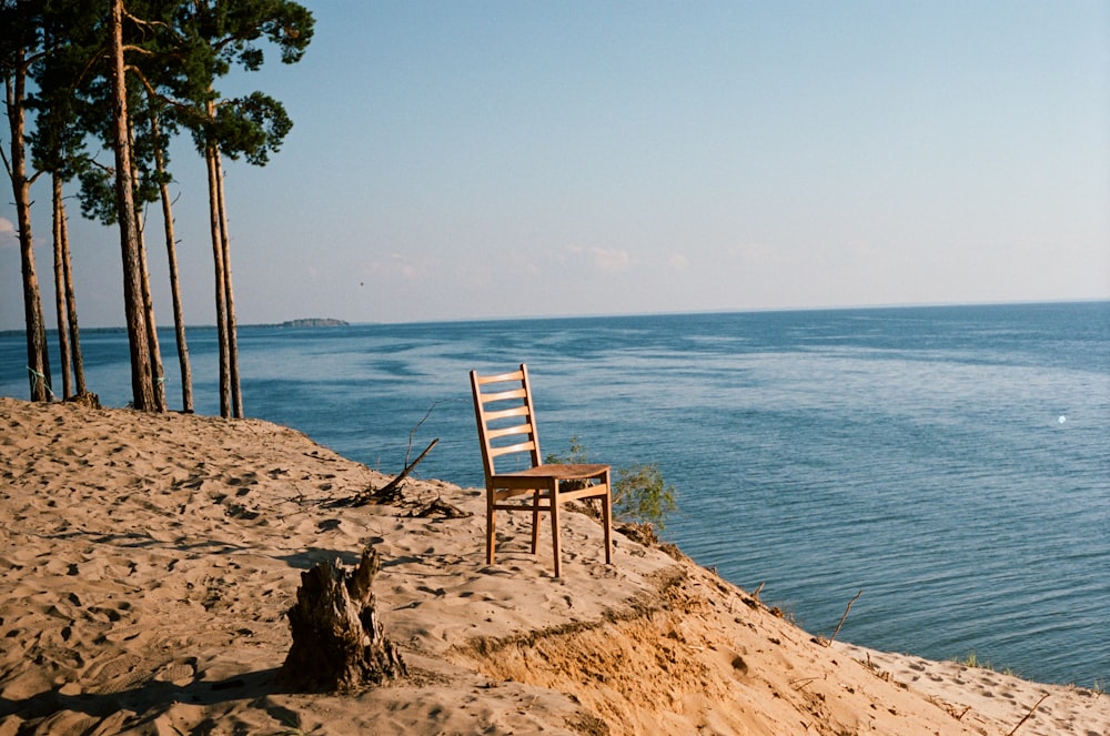 uma cadeira de madeira sentada em cima de uma praia de areia