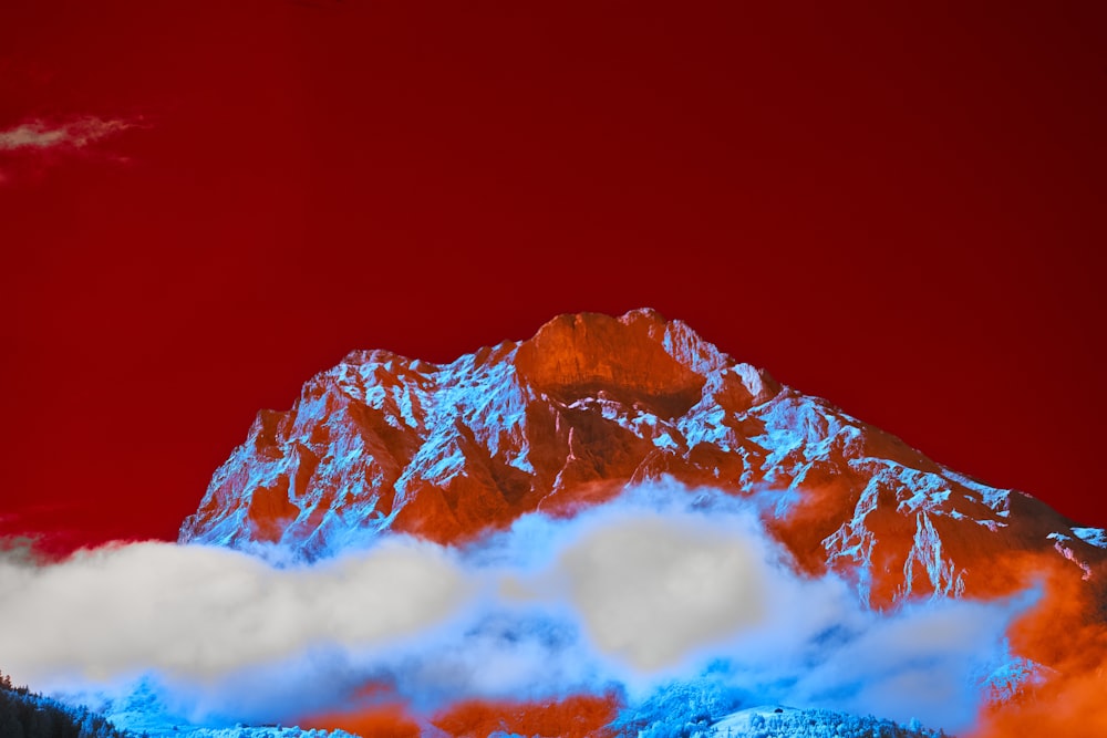a red and blue mountain with clouds in the foreground