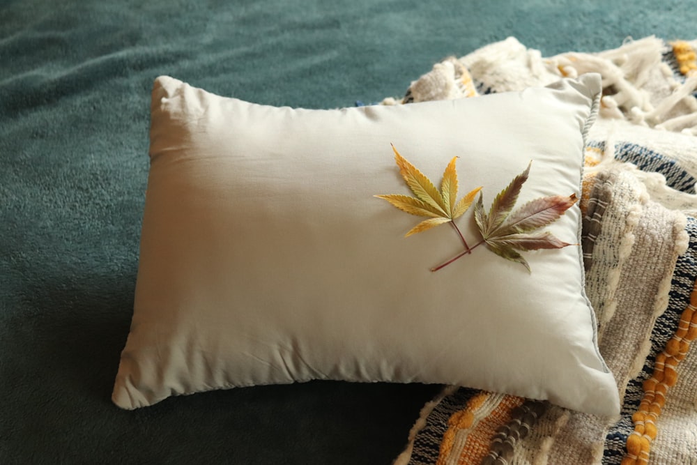a white pillow with a leaf on it