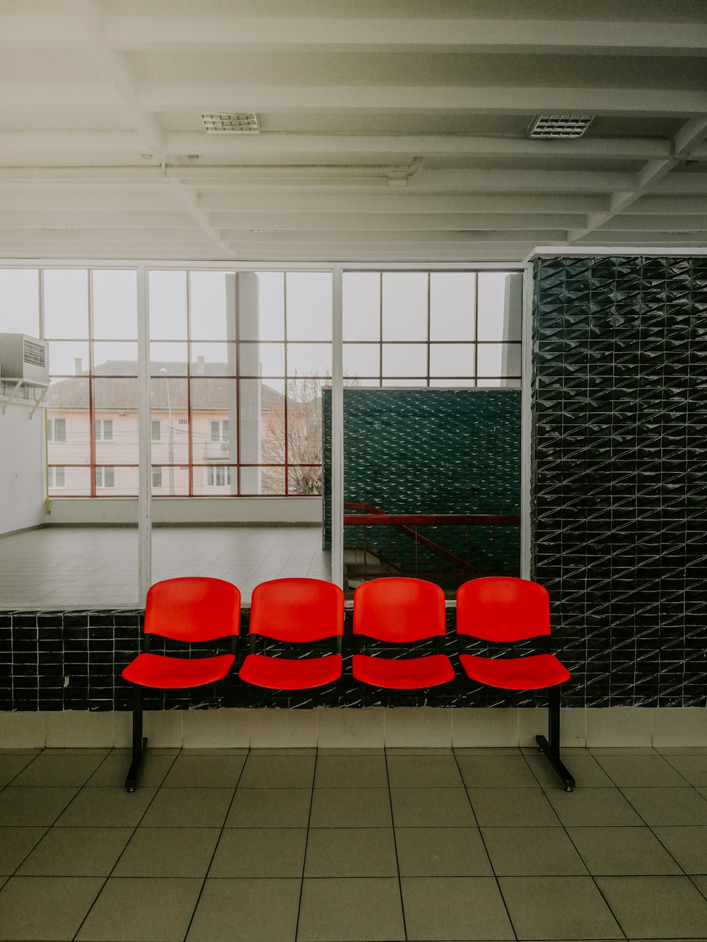 a row of red chairs sitting on top of a tiled floor