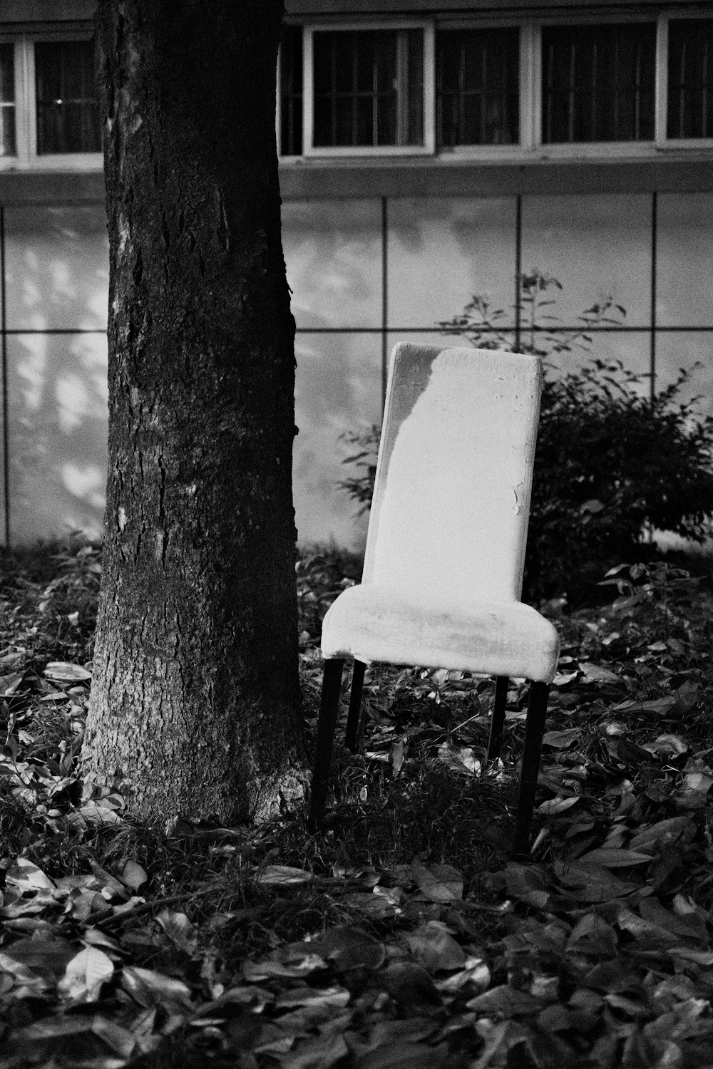 a white chair sitting under a tree next to a building