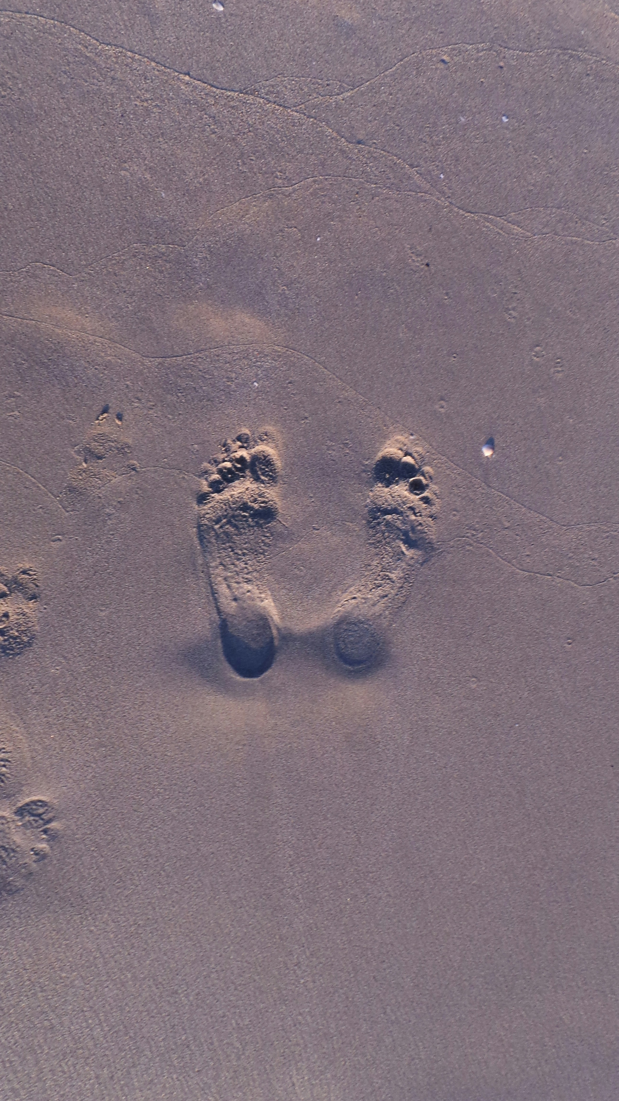 two footprints in the sand of a beach