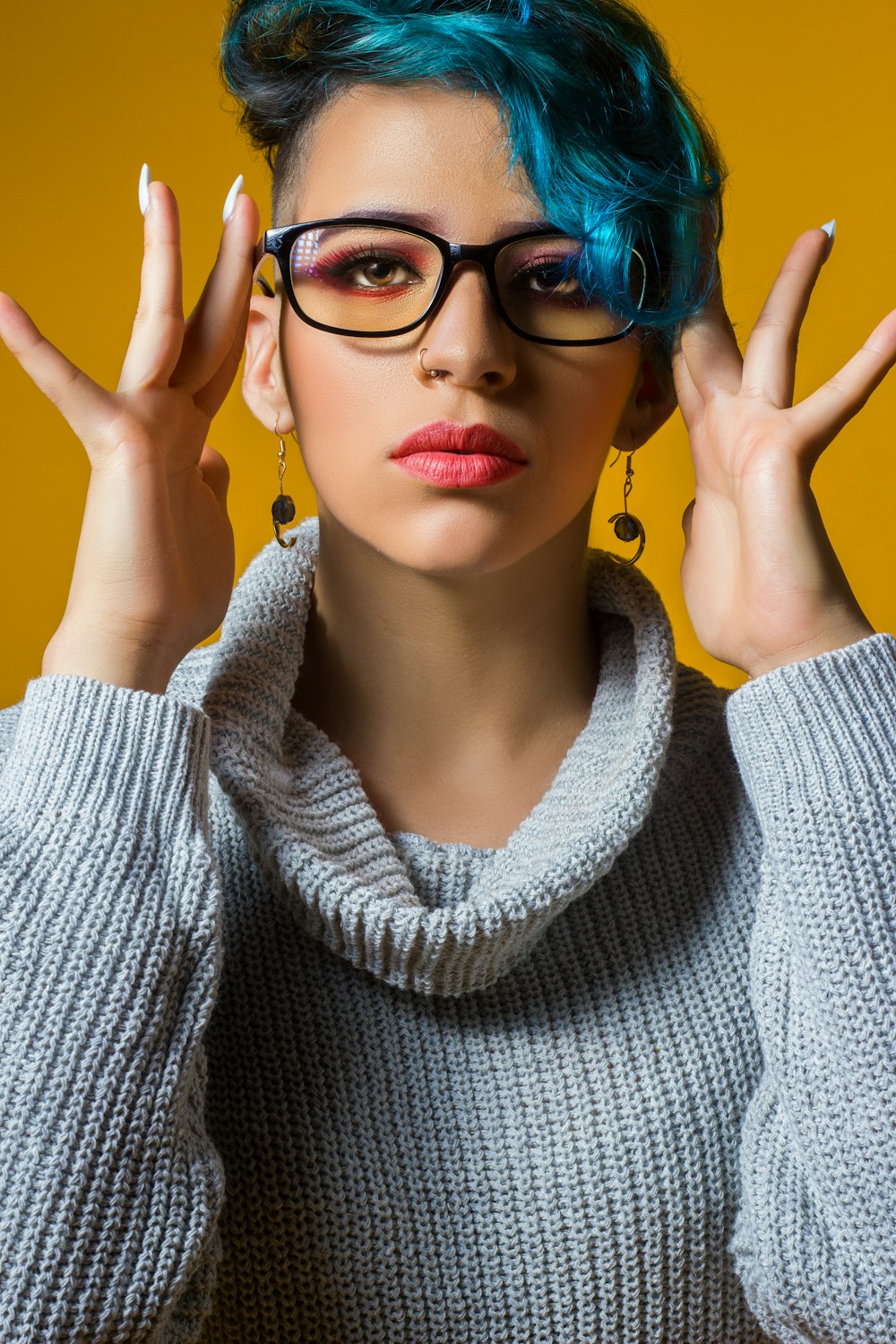 a woman with blue hair wearing glasses and a sweater