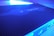 A close-up view of a network device with a perforated surface, labeled 'EdgeRouter 4' under blue LED lighting. The image shows parts of the device's ports and connections on the side.