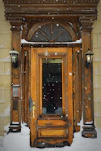 Dimansi doorbell mounted on a modern home’s exterior wall with a smooth snowfall particle effect in the background.