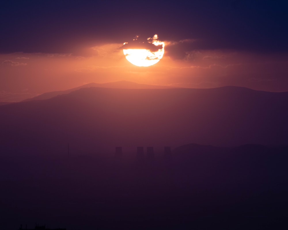 the sun is setting over a mountain range