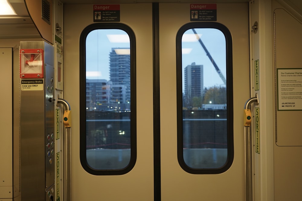 a train door with two windows and a view of a city