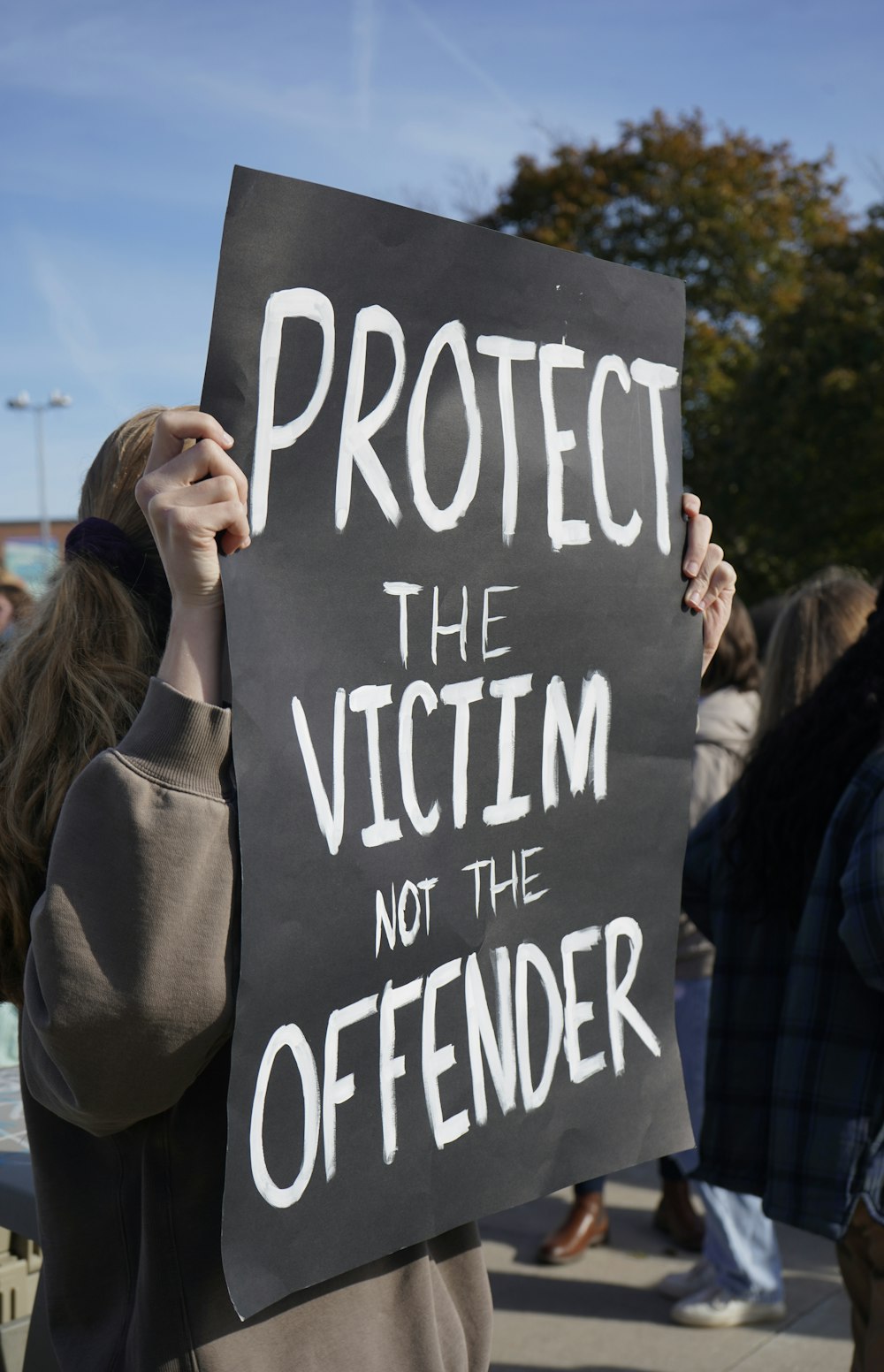 a person holding a sign that says protect the victim not the offender