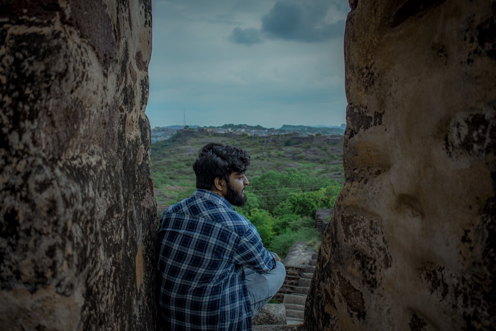 Un hombre mirando por una ventana en una pared de piedra