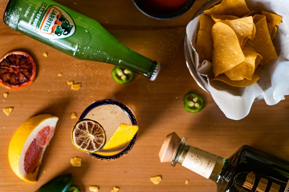 a wooden table topped with a bowl of fruit and a bottle of alcohol