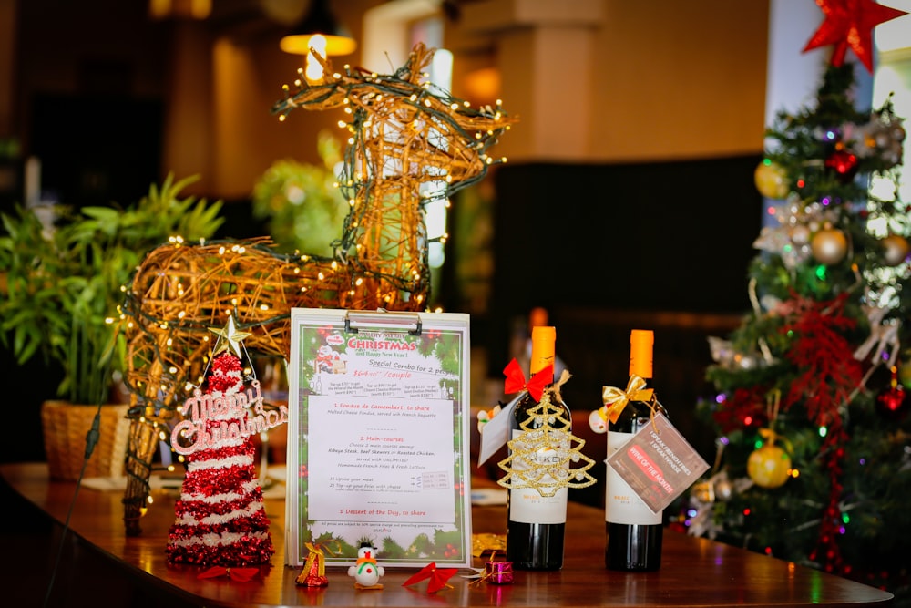 a table topped with bottles of wine next to a christmas tree