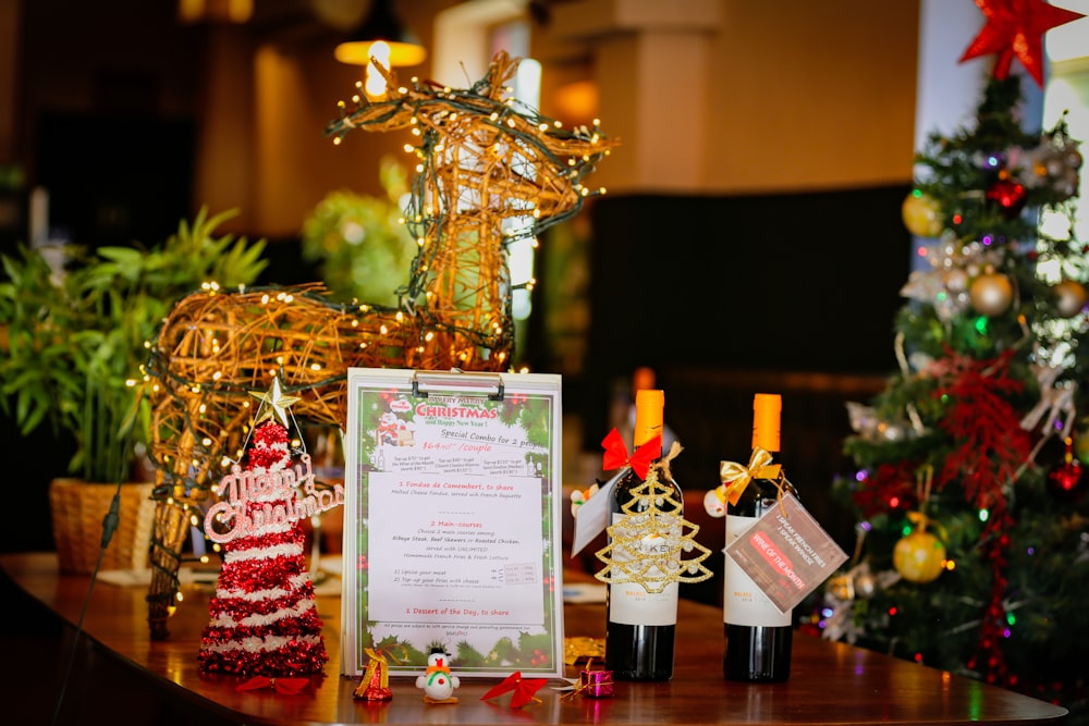 Un tavolo sormontato da bottiglie di vino accanto a un albero di Natale