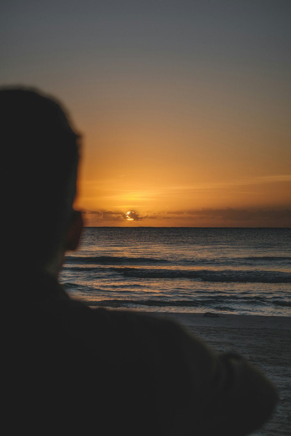 a man standing on top of a beach next to the ocean