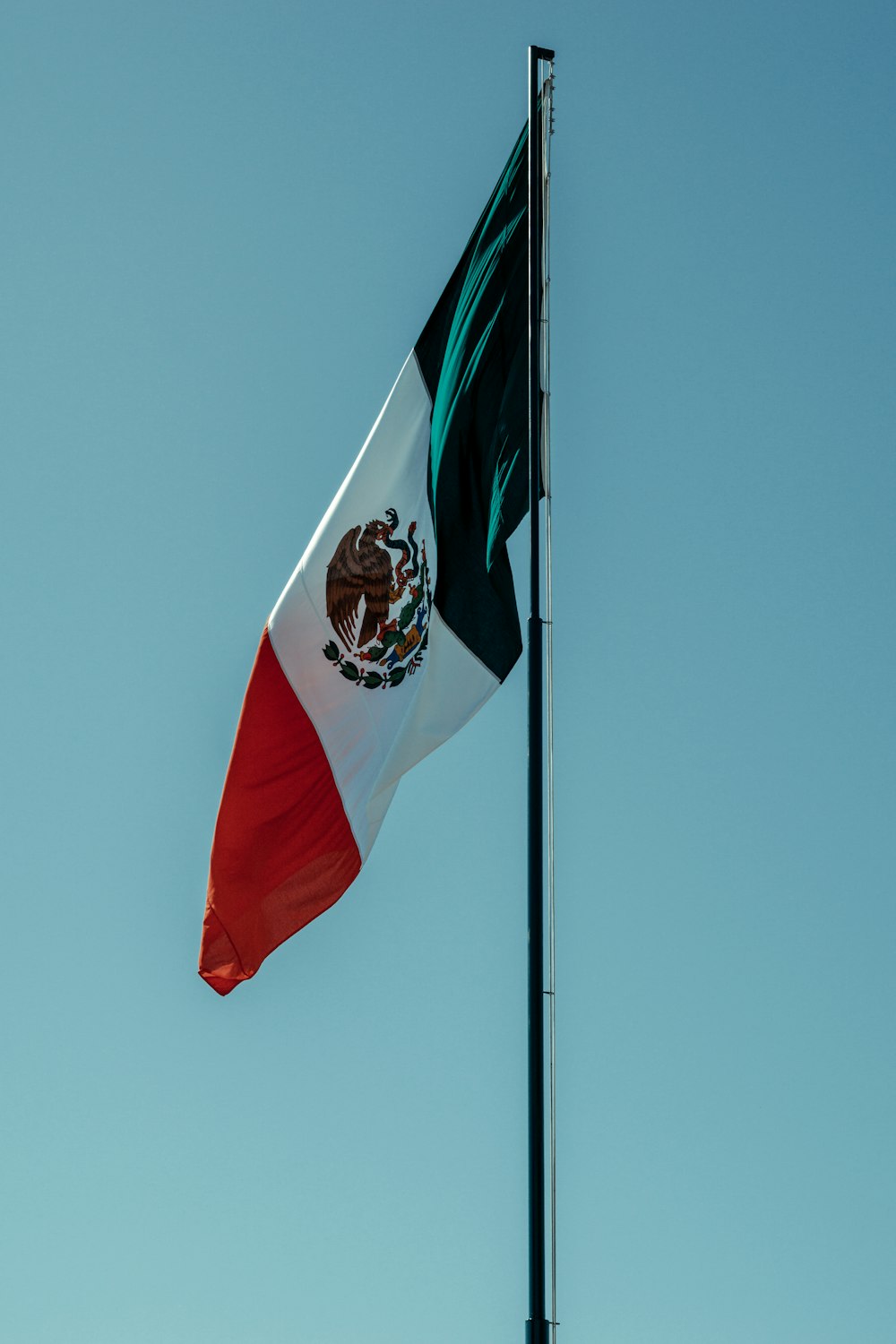 a mexican flag flying high in the sky