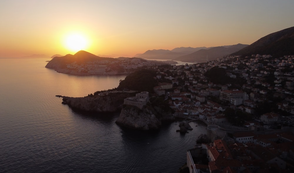 the sun is setting over a small town by the water