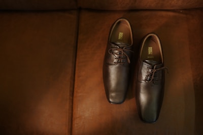 a pair of brown shoes sitting on top of a brown couch