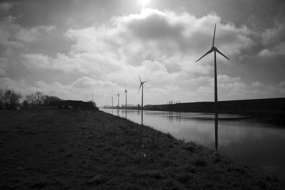 a row of wind turbines next to a body of water