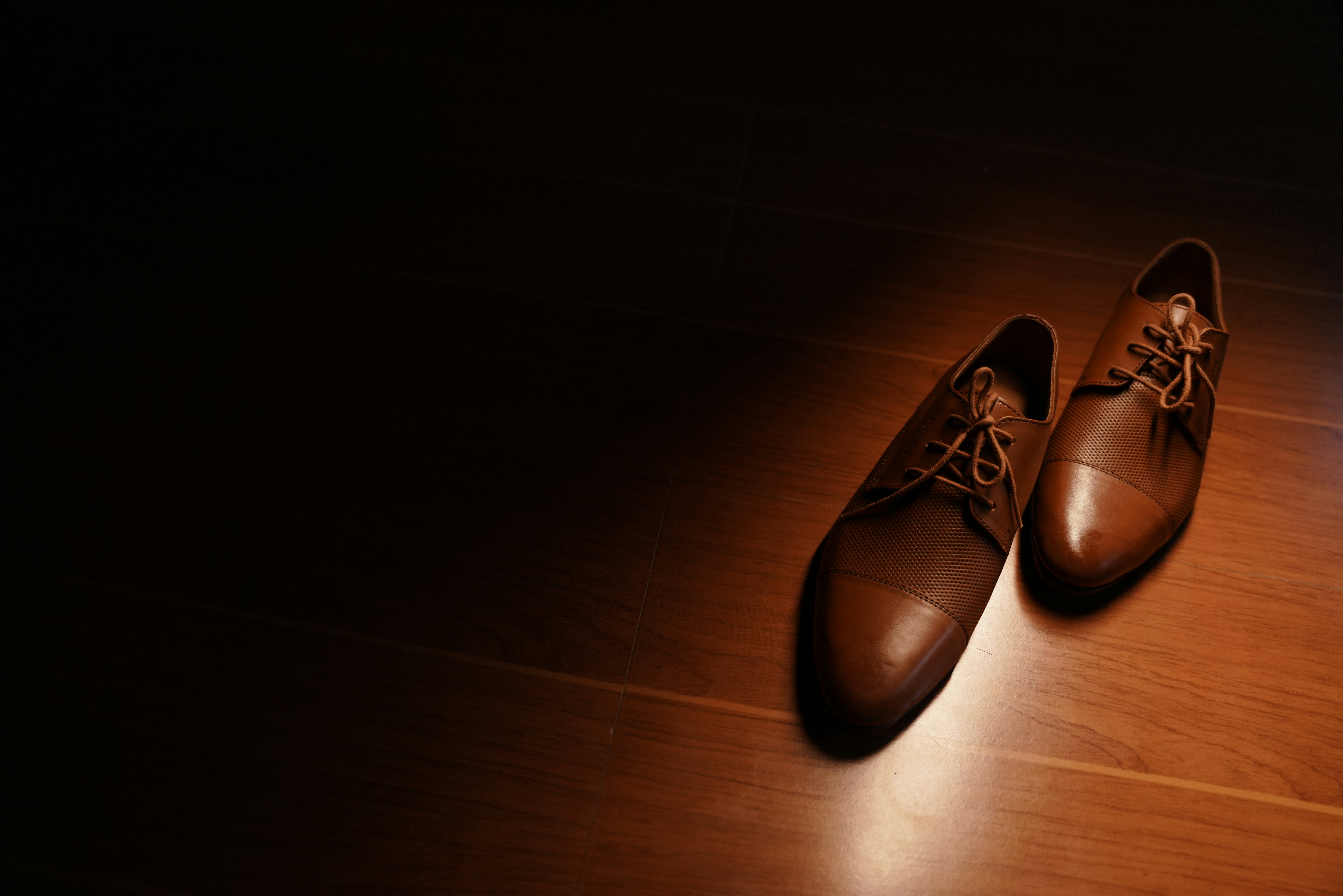 신발이 발 건강에 영향을 주는 방식 - a pair of brown shoes sitting on top of a wooden floor