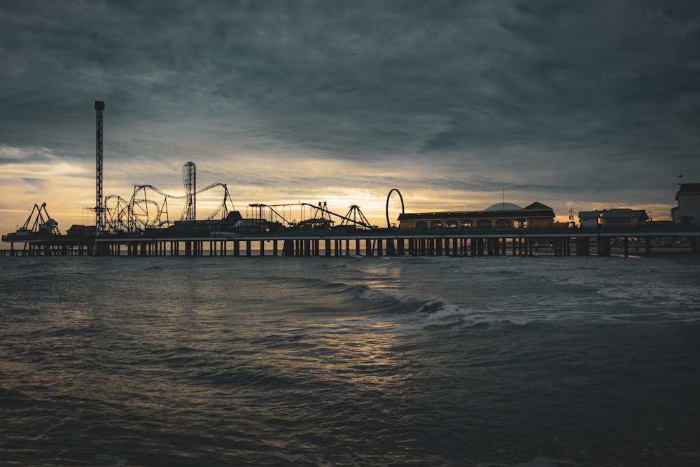 a pier with a roller coaster in the distance