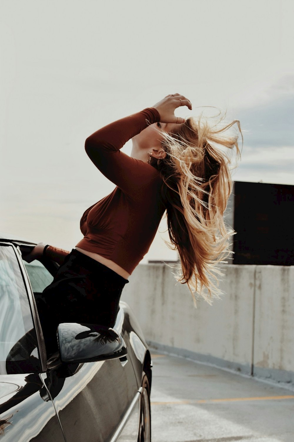 a woman leaning on the hood of a car