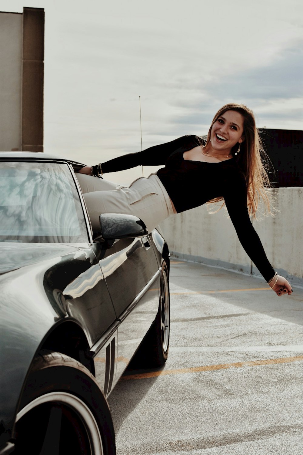 a woman leaning on the hood of a car