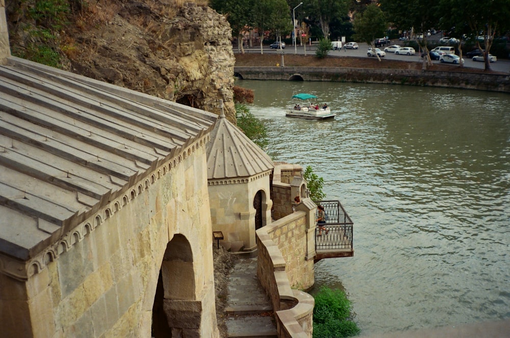 a boat traveling down a river next to a stone building