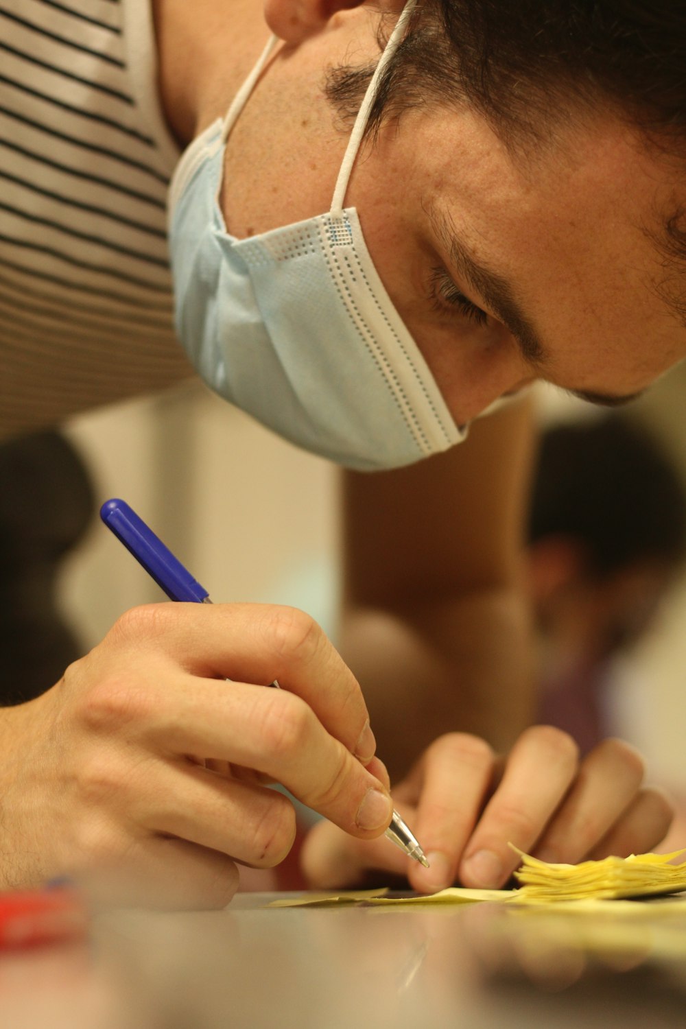 a man wearing a face mask writing on a piece of paper