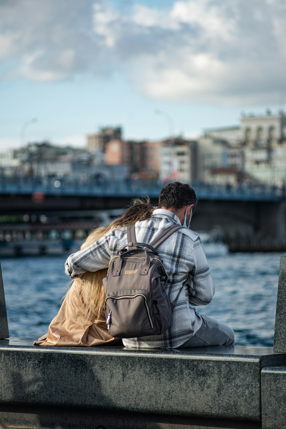 a man and a woman are sitting on a pier