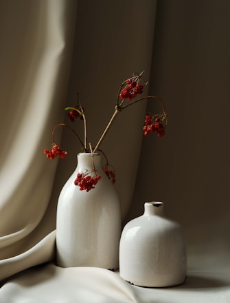 two white vases with red flowers in them