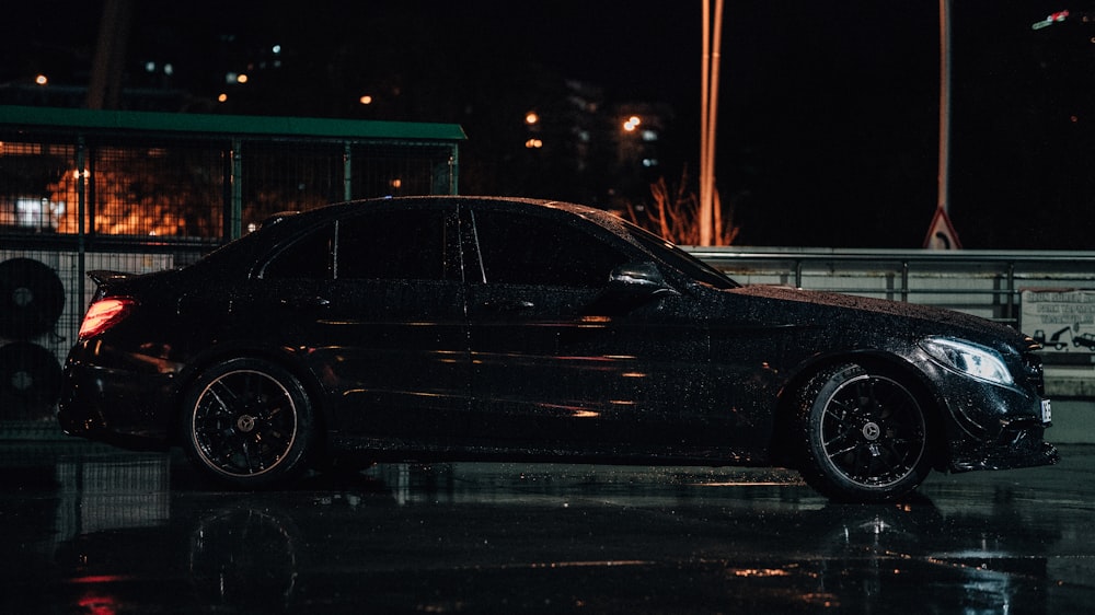 a black car parked in a parking lot at night