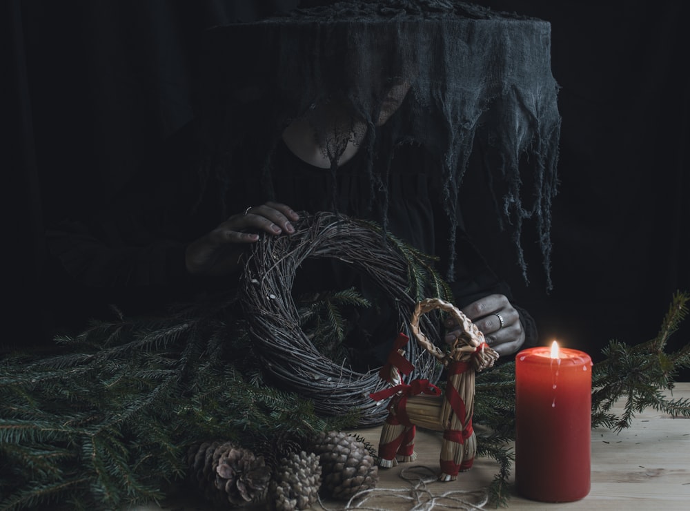 a woman holding a wreath next to a lit candle