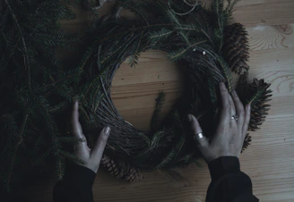 A close-up of hands crafting nature-inspired art with pinecones and twine.