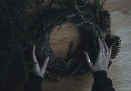 A close-up of hands crafting nature-inspired art with pinecones and twine.