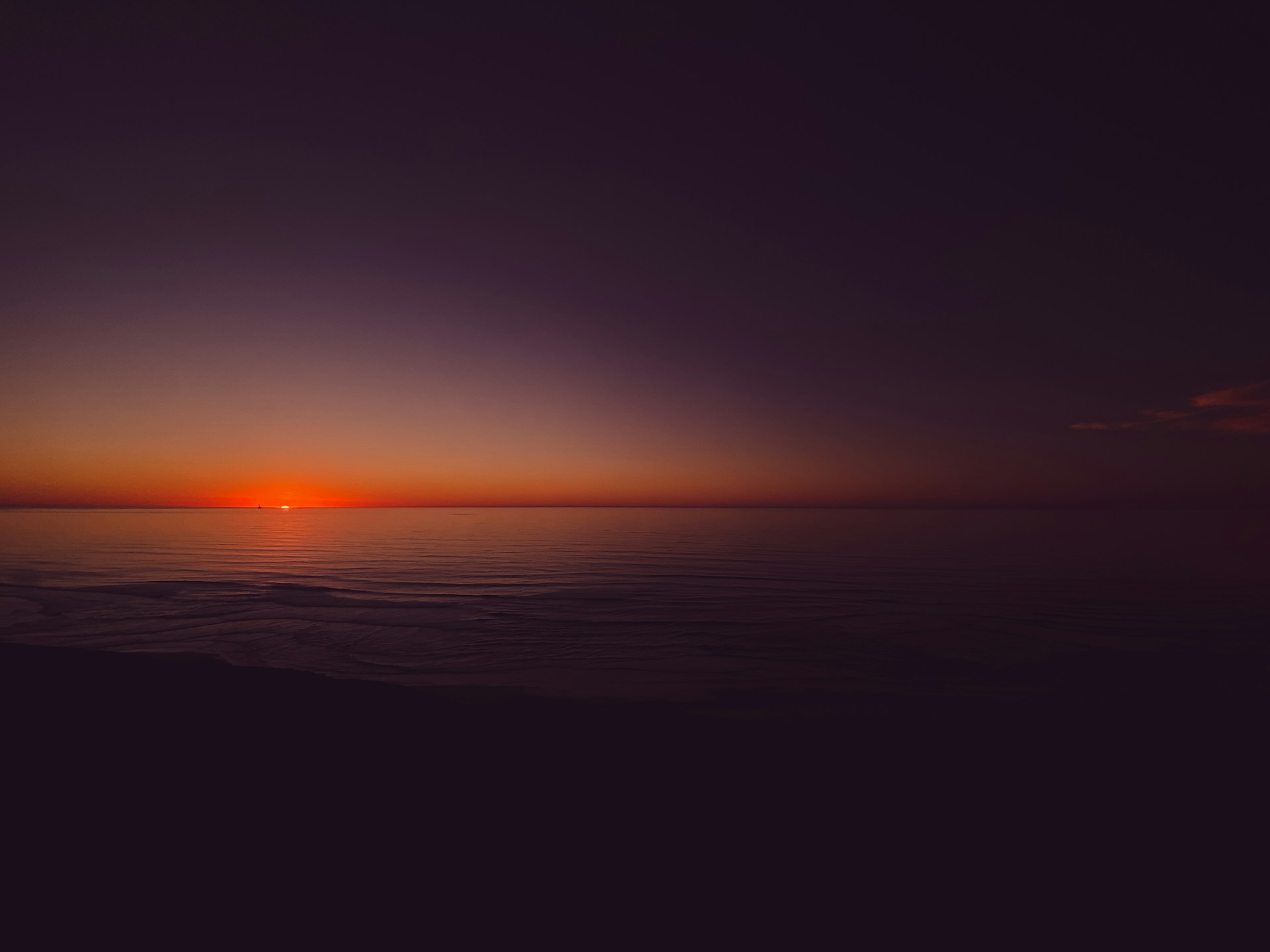 the sun is setting over the ocean on a cloudy day
