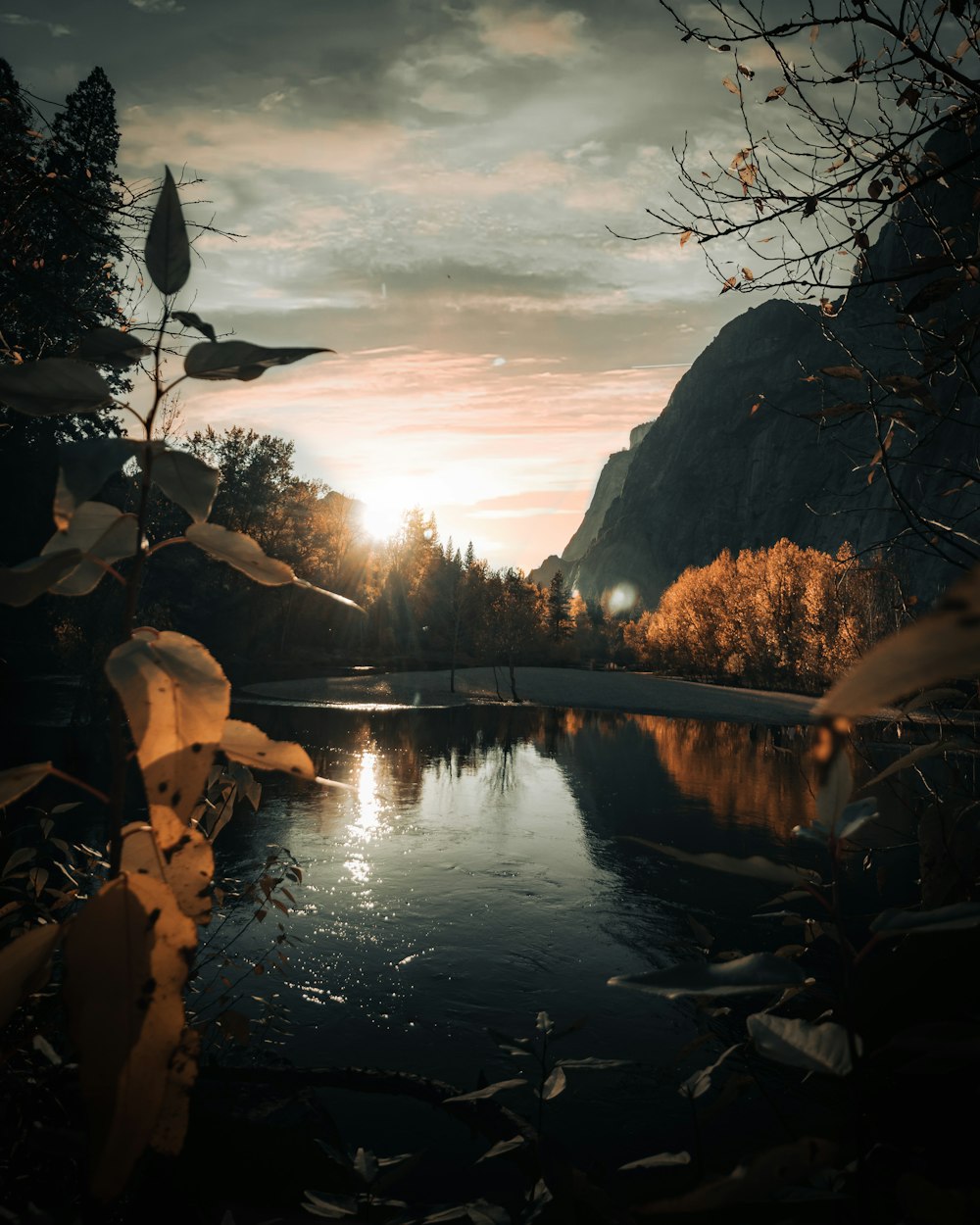 the sun is setting over a mountain lake